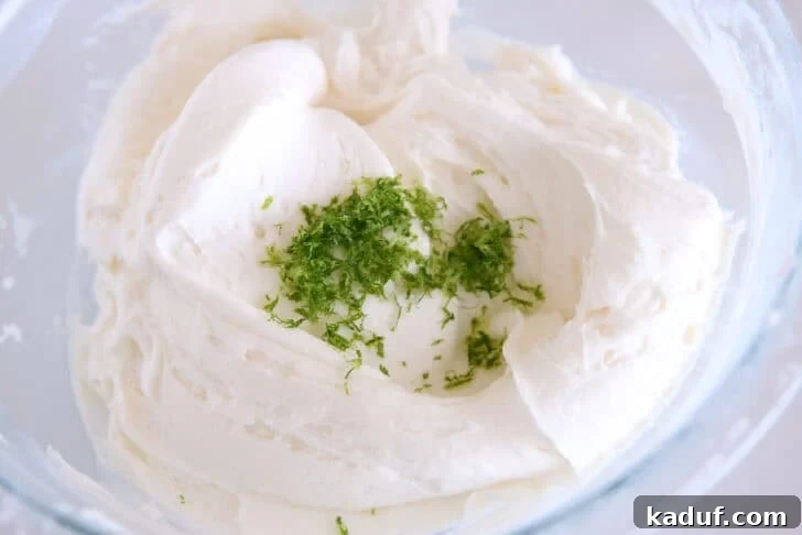 Glass bowl with mixed coconut lime frosting and fresh lime zest.