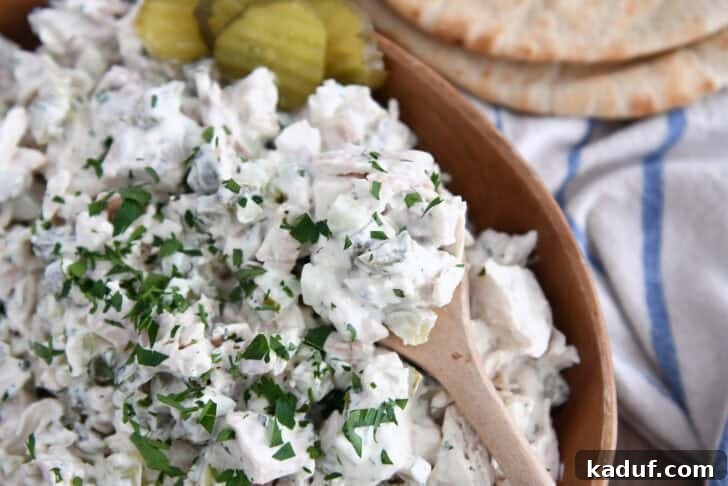Tangy Dill Pickle Chicken Salad Recipe 3 Wooden bowl filled with creamy dill pickle chicken salad with wooden spoon.