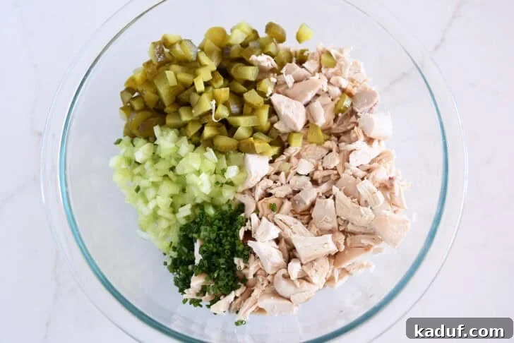 Tangy Dill Pickle Chicken Salad Recipe 4 Glass bowl with chopped chicken, chopped green onions, chopped celery, and chopped dill pickles.