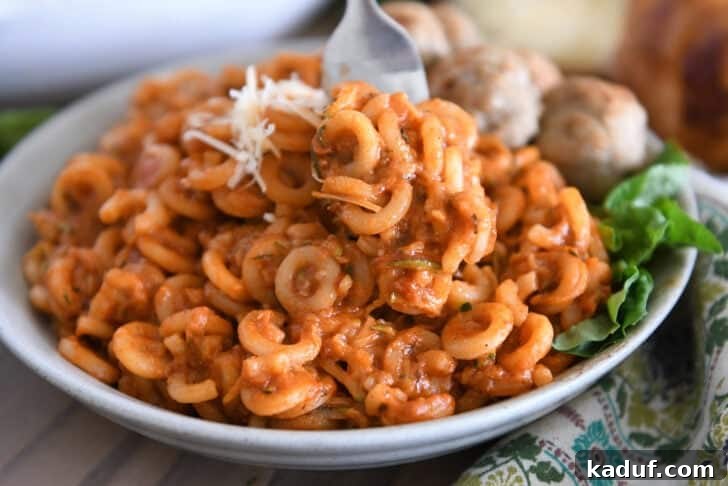 One-Pot Saucy Zucchini Pasta for Quick Weeknight Meals 3 Saucy pasta with shredded zucchini piled high on plate with fork scooping bite.