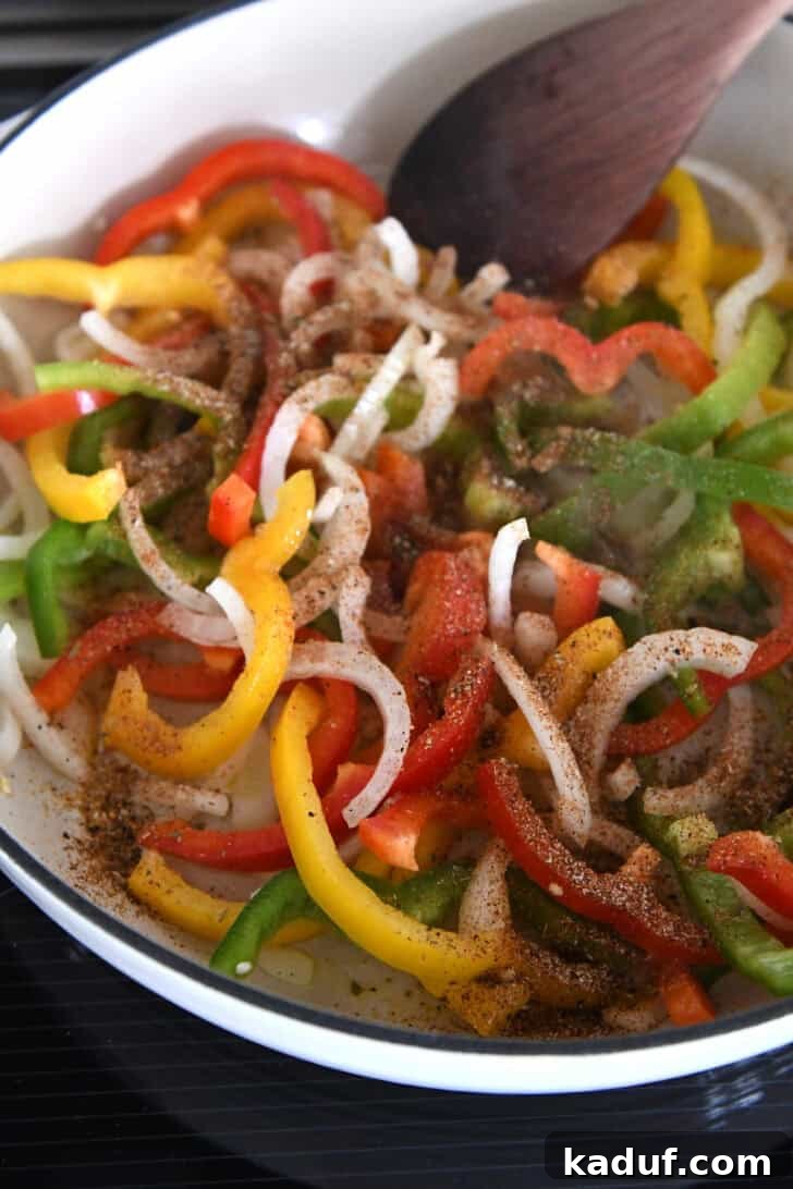 Weeknight Chicken Fajitas with Peppers and Onions 5 White cast iron skillet with sliced onions, bell peppers and fajita seasonings.