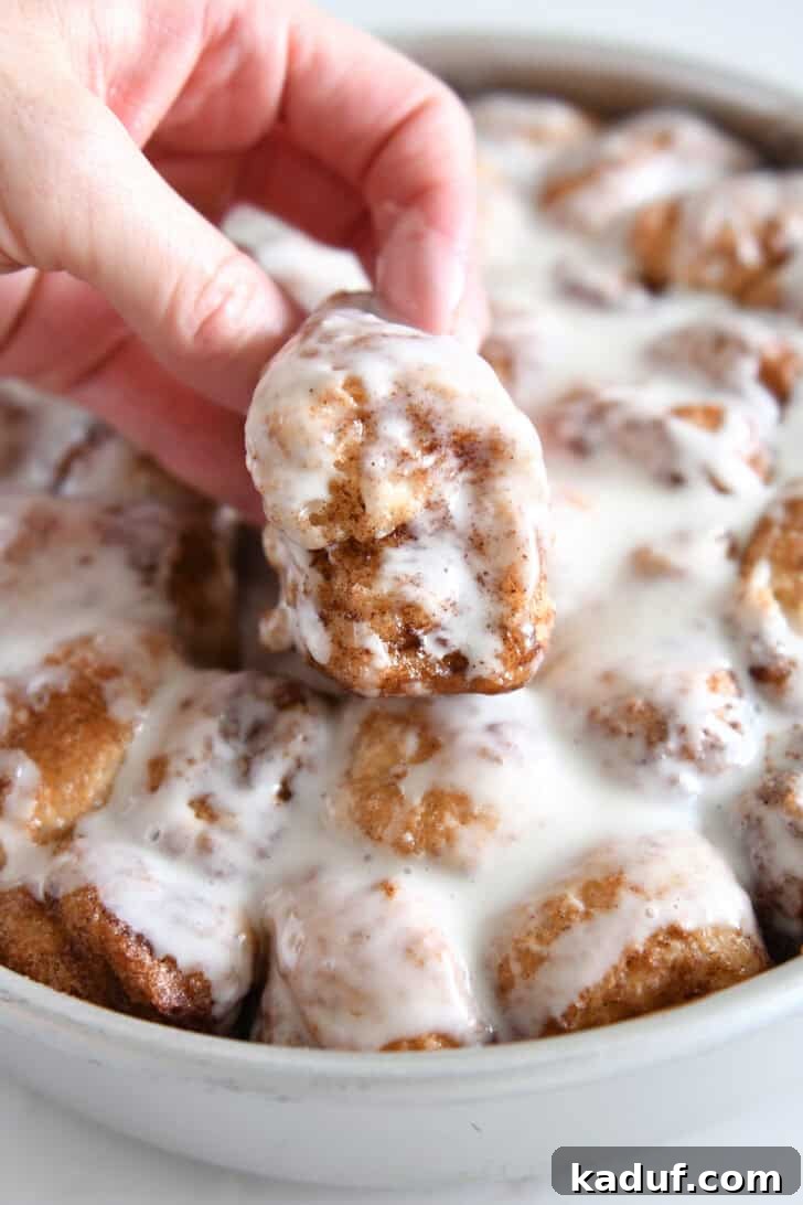 Fluffy Cinnamon Roll Bites: Mini Sweet Pastries 2 Lifting fluffy cinnamon roll bite out of pan of cinnamon roll bites.