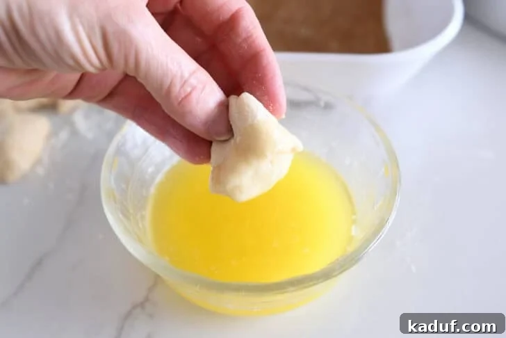 Fluffy Cinnamon Roll Bites: Mini Sweet Pastries 6 Dipping small piece of roll dough in melted butter.